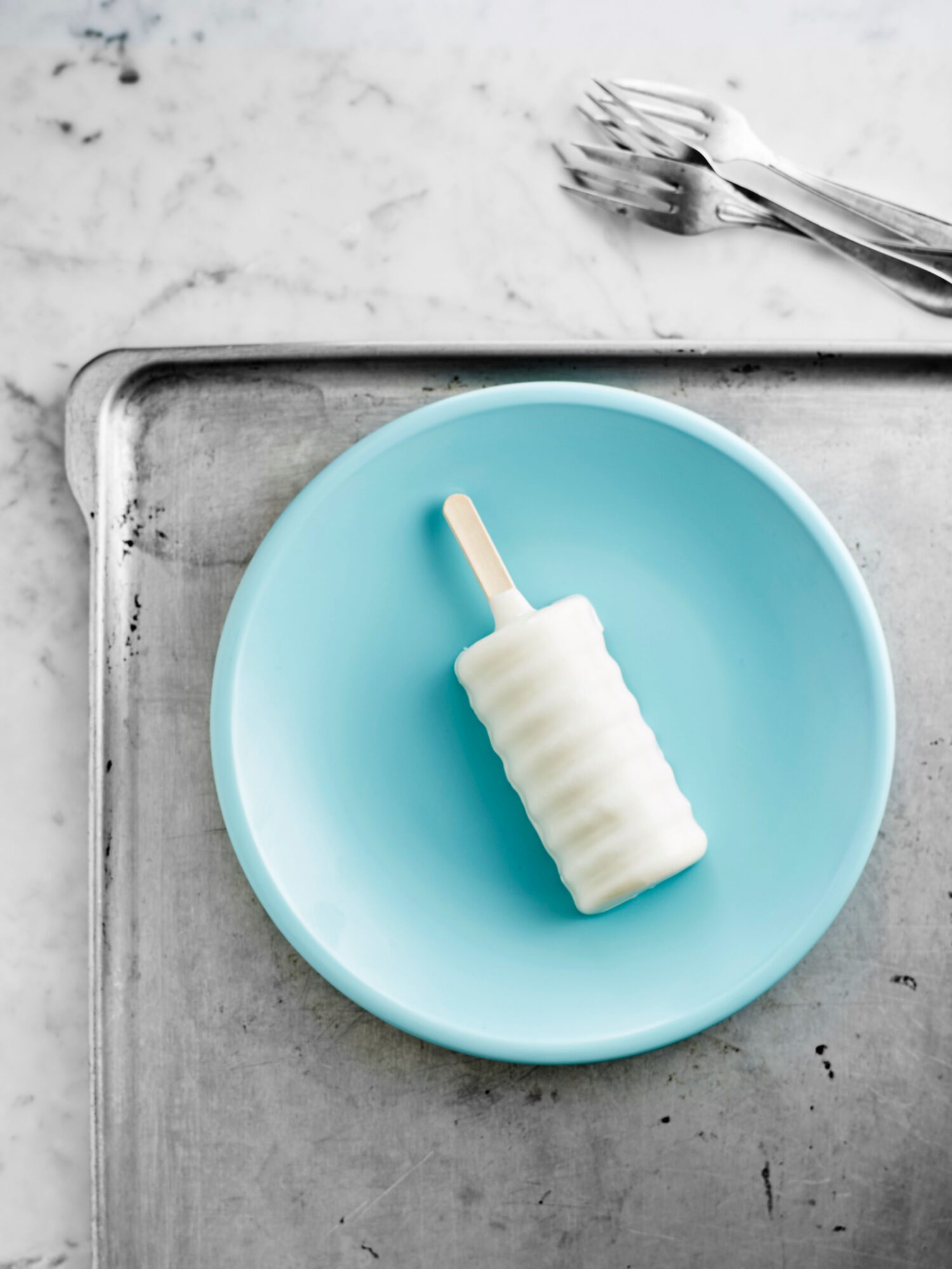Glace au yaourt sur bâtonnet posée sur une assiette turquoise